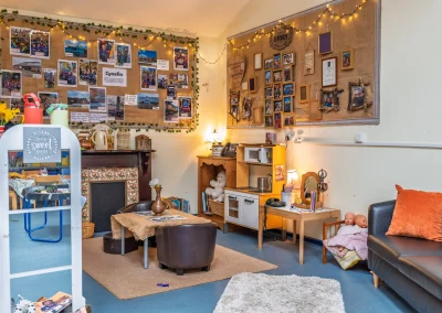Home-corner role-play room with toy kitchen, sofa and family displays at Little Gems preschool