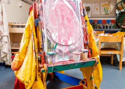 Paint-covered easel and children's artwork in the creative area at Little Gems preschool