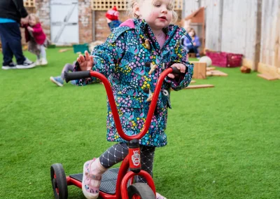 Child riding a tricycle in the nursery garden